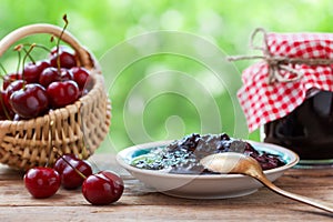 Basket with cherry and jar of jam.