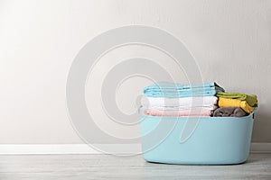 Basket with clean laundry on floor near color wall