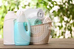 Basket with clean towels and detergents on table against blurred background