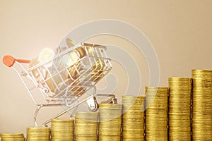 Basket with coins with sun glare and columns of coins on a gray background