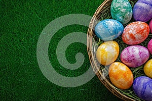 Basket of colorful Easter eggs on green grass background