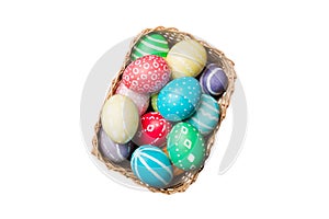 Basket of colorful Easter eggs isolated on white background. Easter basket filled with colored eggs top view holiday