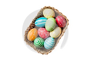 Basket of colorful Easter eggs isolated on white background. Easter basket filled with colored eggs top view holiday