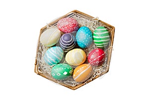 Basket of colorful Easter eggs isolated on white background. Easter basket filled with colored eggs top view holiday