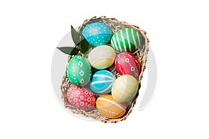 Basket of colorful Easter eggs isolated on white background. Easter basket filled with colored eggs top view holiday