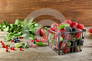 Basket with delicious berries on wooden table