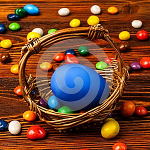 A basket of delicious Easter eggs and sweets on wooden background