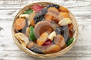 Basket with dried fruit, tutti frutti, on wooden background