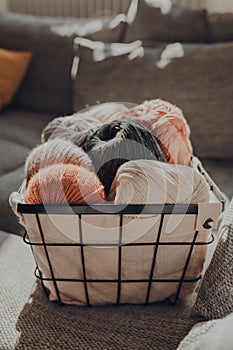 Basket of earth coloured skeins of yarn on a sofa, selective focus