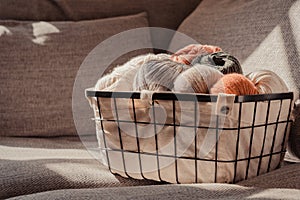 Basket with earth coloured yarn on a sofa, sunlight and warm tones