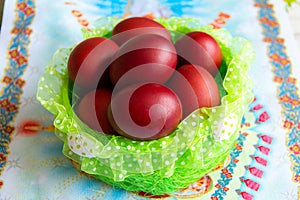 Basket with easter cake and red eggs on rustic wooden table. Top view.