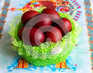 Basket with easter cake and red eggs on rustic wooden table. Top view.