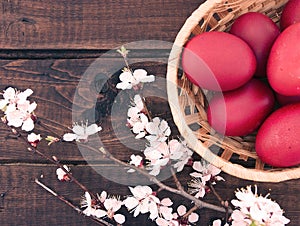 Basket with easter red eggs on rustic wooden table. Holiday back