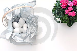 Basket with eggs and cyclamen flower. minimalistic composition for Easter. top view
