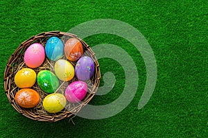 a basket filled with colorful easter eggs on a green grass background