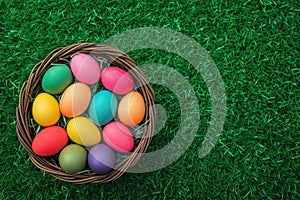 a basket filled with colorful easter eggs is sitting on top of a lush green field
