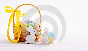 Basket with flowers and decorated eggs for the Easter holiday. Colorful eggs in egg stands. Homemade rabbit cookies