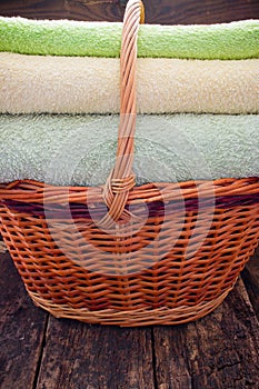 Basket with fresh clean colorful towels on a wooden