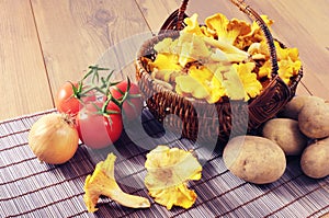 Basket with fresh golden chanterelles and potatos tomatos on tab