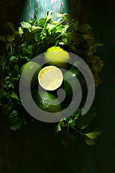 Basket with fresh organic greens, avocado and lime on a dark green background. Monochrome.
