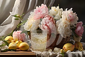 A basket of fresh peonies and irises in pastel colors on a white tablecloth with a glass of lemonade