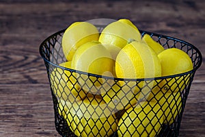 Basket of fresh yellow lemons on a rustic wood table