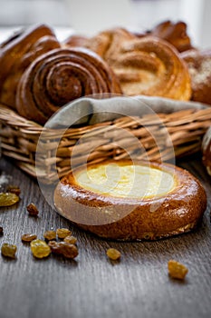 Basket of freshly baked dinner rolls with tableware in wooden background. Macro with shallow dof