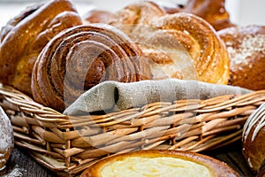 Basket of freshly baked dinner rolls with tableware in wooden background. Macro with shallow dof