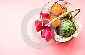 Basket with fruit on blue background. watermelon and oranges on pink pastel background