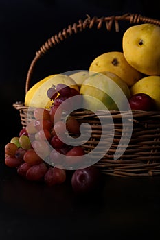 Basket of full of fruits with summer seasonal fruits farm fresh mangoes and red wine grapes