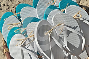 Basket Full of Pairs of Flip Flop Sandals in White as well as Turquoise Blue at the Beach