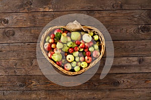 Basket full of ripe apples and pears on a wooden background. View from above. Flat lay. Copy space. Harvest concept