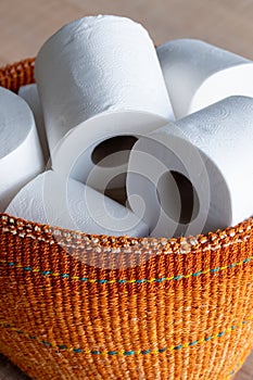 Basket full of white toilet rolls, illustrative of stockpiling toilet rolls during the corona virus pandemic.