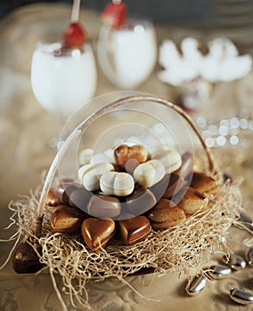 Basket with heart-shaped chocolates with two glasses of coktail still life