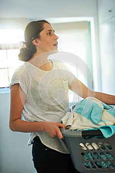 Basket, laundry and woman in home with chores, busy work and housekeeping routine. Washing, dirty clothes and housewife