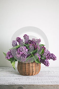 Basket of lilac flower on white wooden background. Vintage toned. Mothers and womens day