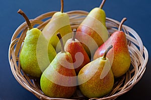 Basket with pears on dark wooden background. Harvest concept. Top view flat lay overhead