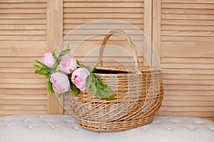 Basket with peony flowers on a wooden background