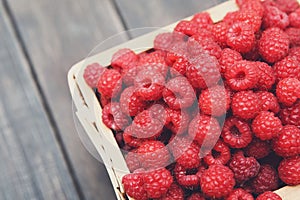 Basket with raspberries on wooden table