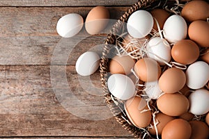 Basket with raw chicken eggs on wooden background, top view