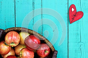 Basket of red apples on wood table with red heart