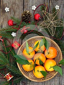 Basket of ripe mandarins, spruce branches and christmas toy on a wooden background. selective focus.