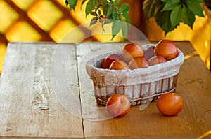 Basket with ripe plums on a rustic table
