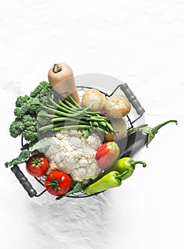 Basket with seasonal vegetables - broccoli, pumpkin, cauliflower, tomatoes, string beans on a light background, top view