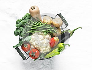 Basket with seasonal vegetables - broccoli, pumpkin, cauliflower, tomatoes, string beans on a light background, top view