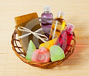 Basket with soap, gel and other bath and shower accessories on bamboo mat