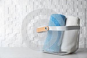 Basket with soft bath towels on table.