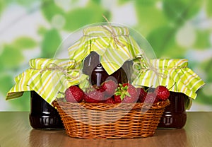 Basket with strawberry and three jam banks