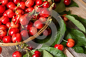 Basket of sweet and ripe cherries with leaves on wooden background photo