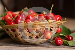 Basket of sweet and ripe cherries with leaves on wooden background photo